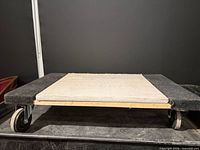 Top view of wooden dolly showing carpet pads and fabric surface