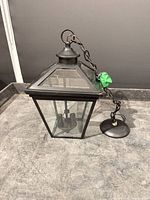 Overall view of black metal and glass hanging lantern with chain and canopy