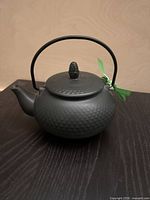 Front view of black cast iron teapot with arched handle and lid