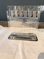 Front view of clear acrylic DEIK knife block, showing 10 slots and black base
