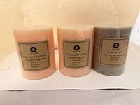 Front view of three Hometrends pillar candles with labels visible