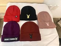Five beanies laid out showing logos on cuffs