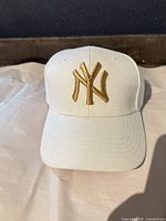 Front view showing gold embroidered NY logo on white cap
