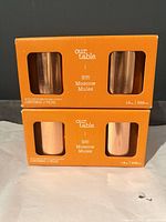 Front view of two orange Our Table boxes with window showing copper mugs