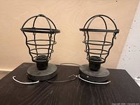 Two black wire-cage light fixtures front view