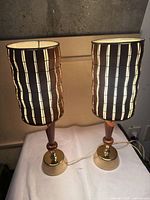 Both lamps illuminated showing wood shades and brass bases