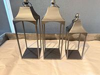 Front view of three black metal lanterns showing two medium and one small sizes