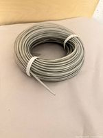 Coiled cable with clear jacket and silver conductor, one cable tie visible