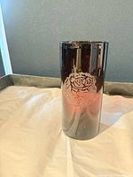 Front view of smoky amber cylindrical glass vase with etched rose