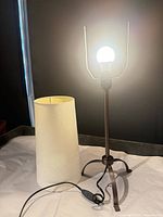 Lamp assembled with bulb lit, shade placed beside