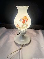 Lamp illuminated showing boy motif and milk glass construction