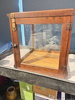 Front three-quarter view showing oak frame, glass panels, brass latch, hinged door