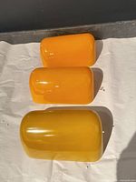 Three yellow porcelain banker lamp shades displayed top view