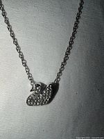 Necklace laid flat showing swan pendant and chain