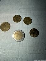 Five euro coins on white textured surface, denominations visible