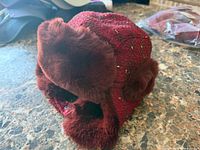 Side view of burgundy trapper hat showing faux fur trim and ear flaps