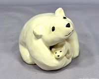 Front view of signed ceramic mother polar bear hugging cub sculpture