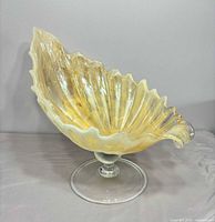 Front view showing shell-shaped bowl, ruffled rim, clear pedestal base