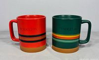 Front view of red and green Pendleton mugs side by side