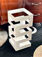 front angle showing stacked geometric design of white metal umbrella stand