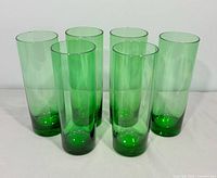 Front view of all six emerald green highball glasses standing in two rows