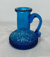 Front view of blue hobnail cruet bottle showing pattern and handle