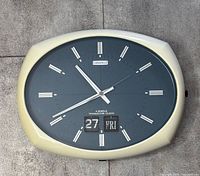 Full view of Caravelle wall clock showing oval cream case and blue face