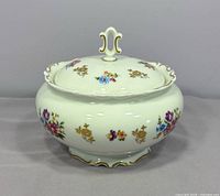 front view of porcelain lidded bowl showing floral pattern, gold trim and scalloped edges