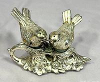 Front view of two bird shakers on floral branch stand