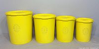 front view of four graduated yellow canisters showing size comparison and embossed design