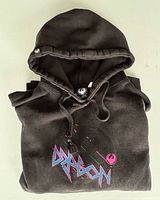 Folded hoodie showing hood, drawstrings and chest logo