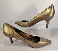 Side profile of both pumps showing gold python texture and heel