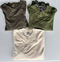 Three folded pullovers showing colors and styles