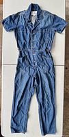 Front view of blue denim jumpsuit laid flat