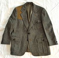 Front view of blazer showing herringbone pattern, suede shooting patch, flap pockets, buttons, lapel