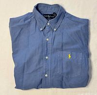 Folded blue Ralph Lauren oxford shirt showing front, chest pocket, and logo