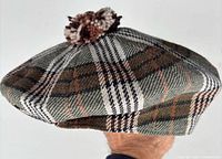 Side view of tartan newsboy cap showing pattern and pom-pom