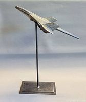 Left side view of chrome jet hood ornament on tall stand