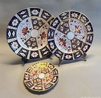 Front view showing all three Royal Crown Derby plates, two on stands one lying flat