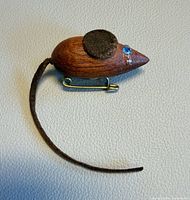 Front view of teak mouse brooch showing felt ears, rhinestone eyes, leather tail and brass clasp