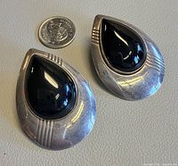 Front view of both earrings next to quarter for scale