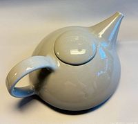 Top angle of porcelain teapot showing lid, handle, spout