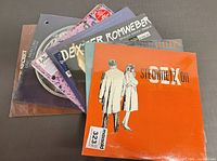 Five stacked sealed LPs, showing shrink wrap and partial titles