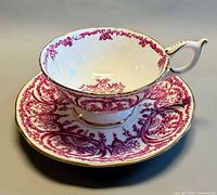 Teacup resting on saucer showing exterior pattern and gold trim