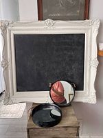 Ornate cream framed chalkboard, two round mirrors, wood tray visible
