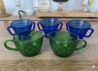 Front view showing three cobalt ribbed sugar bowls and two green ivy-leaf pieces