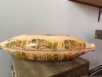 Side view of closed baker showing painted fish motif and overall condition