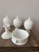 Full grouping of three covered candy dishes, one candle holder and one open dish base on table