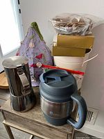 Group shot of all items: espresso maker, travel mug, lampshade, metal bucket, cutlery