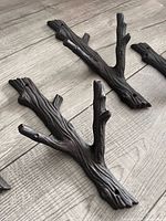 Four cast iron branch hooks on wood floor, showing overall form and finish